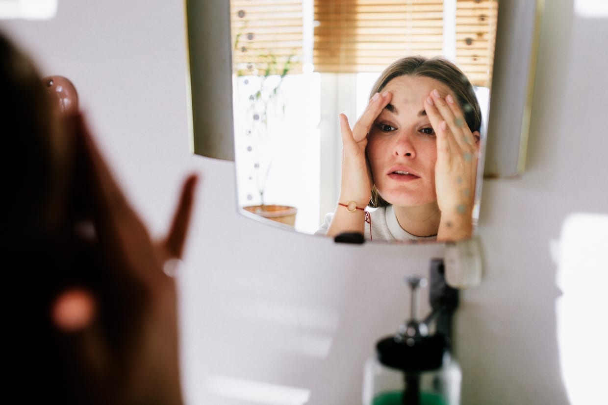 Woman looking in bathroom mirror after cleaning her face.