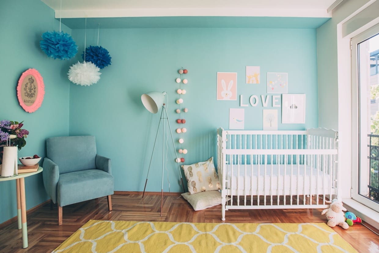 Nice decorated turquoise nursery with white crib.