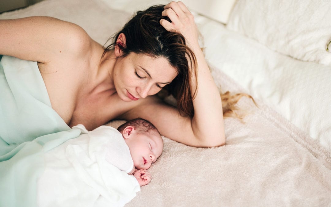 A mother and her newborn on a bed.