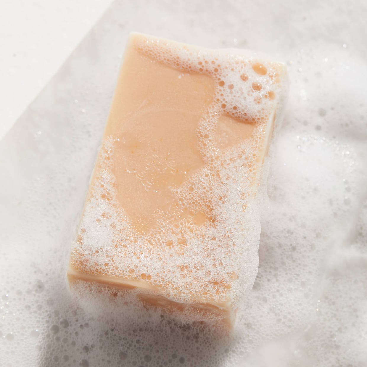 A peach colored conditioner bar with suds.