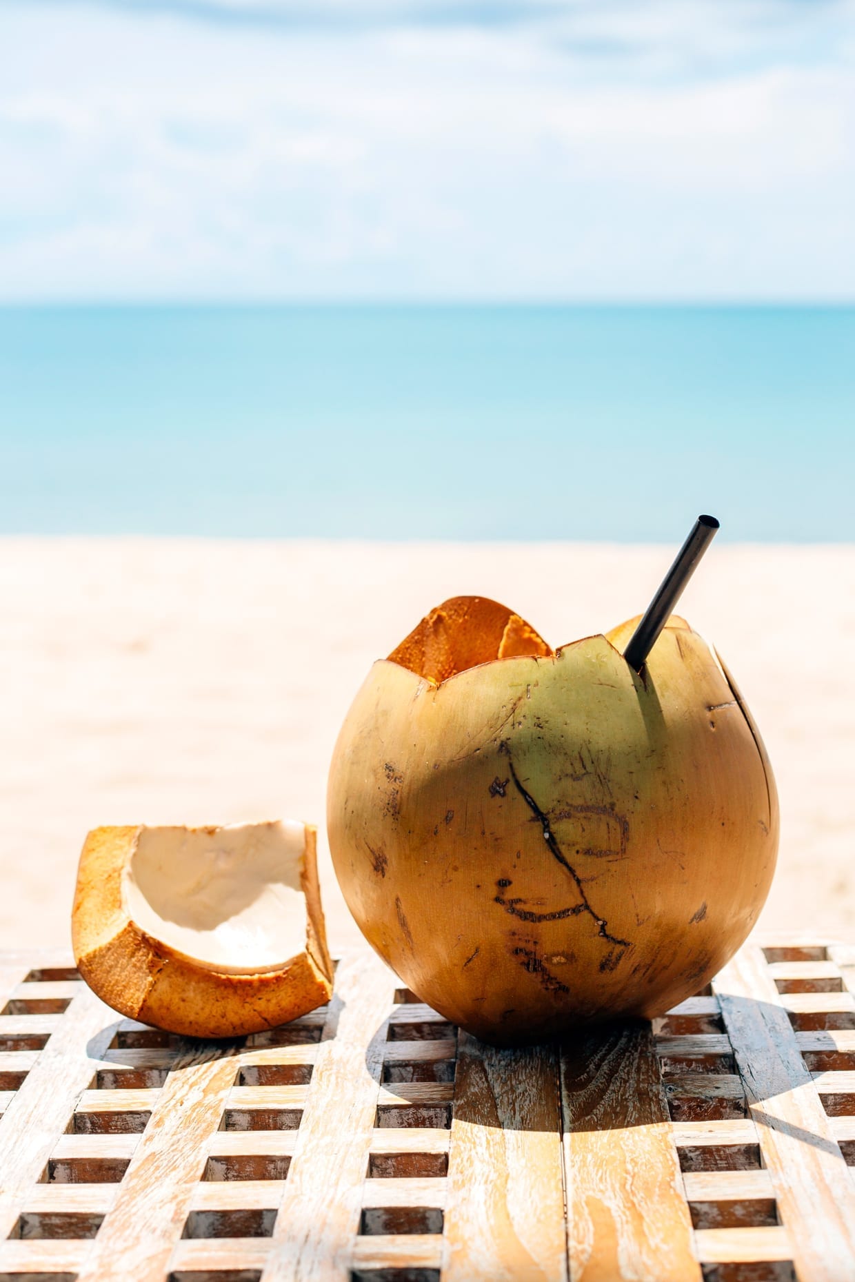 A coconut cut open with a straw on a table.