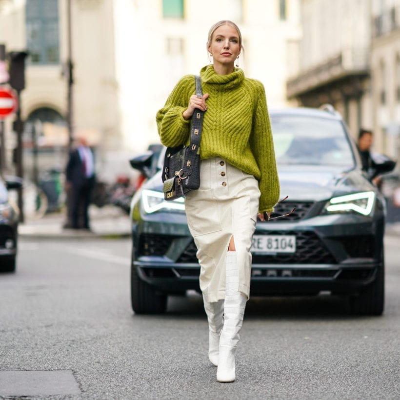 Leonie Hanne wears a green wool turtleneck knitted pullover, a Givenchy bag, white side slit skirt, white high boots, during Paris Fashion Week, Sept. 30, 2019.