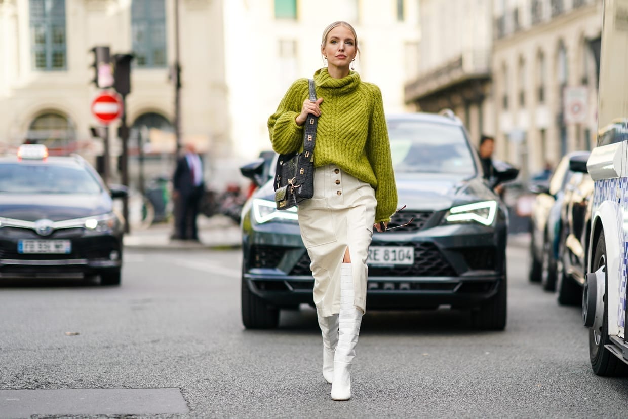 Leonie Hanne wears a green wool turtleneck knitted pullover, a Givenchy bag, white side slit skirt, white high boots, during Paris Fashion Week, Sept. 30, 2019.