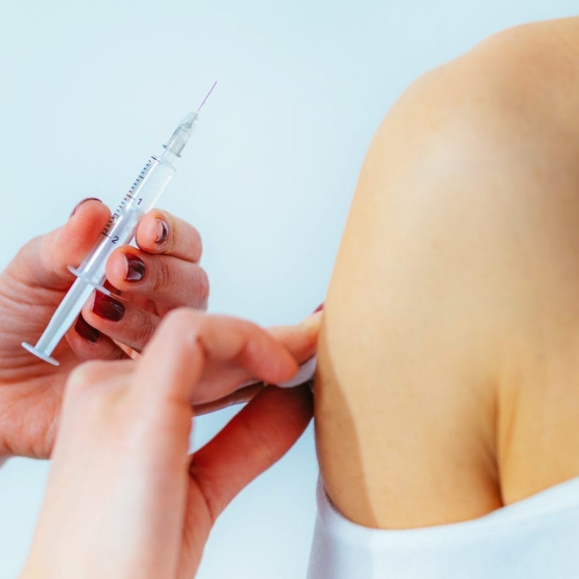 Female doctor injecting a syringe into a woman's shoulder.