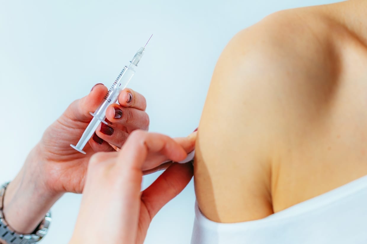 Female doctor injecting a syringe into a woman's shoulder.