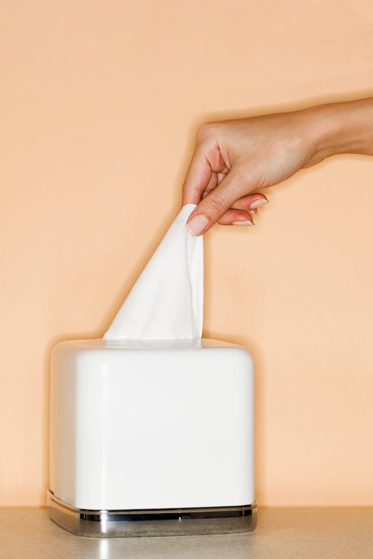 A woman pulling a tissue out of a box.