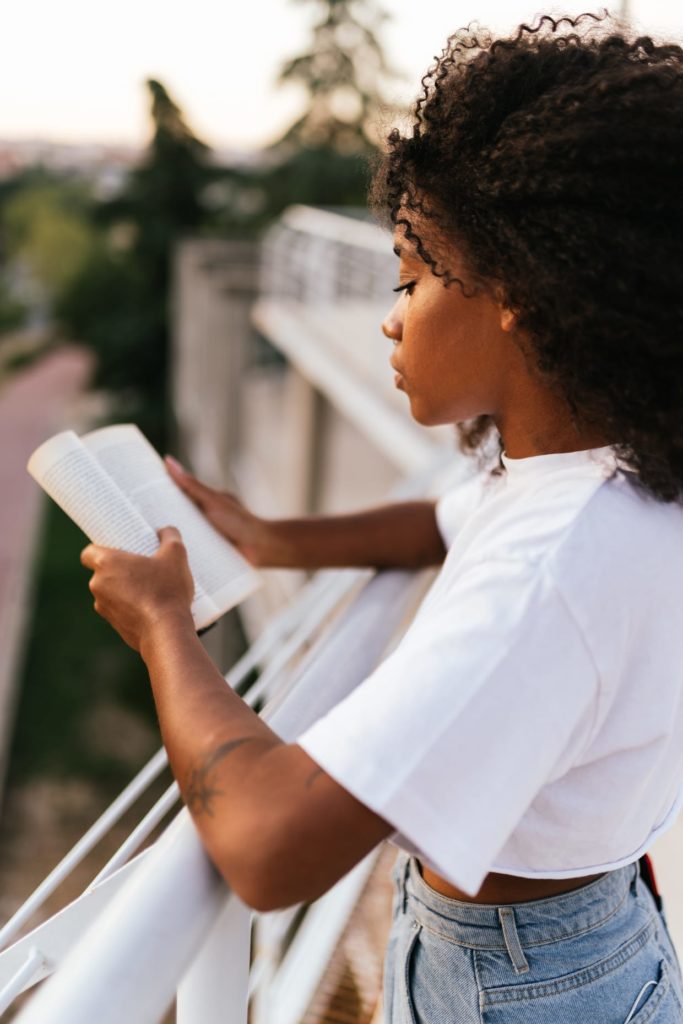 Side view of a black woman reading a book.