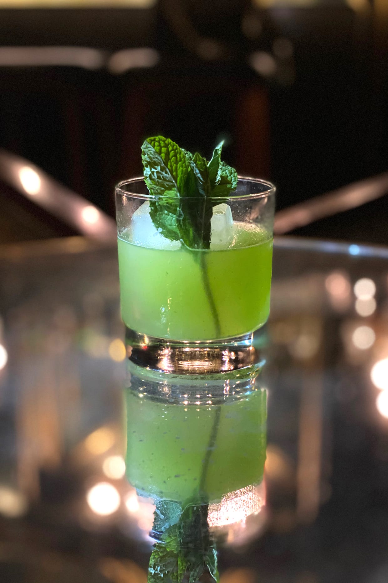 A green mocktail in a rocks glass with mint.