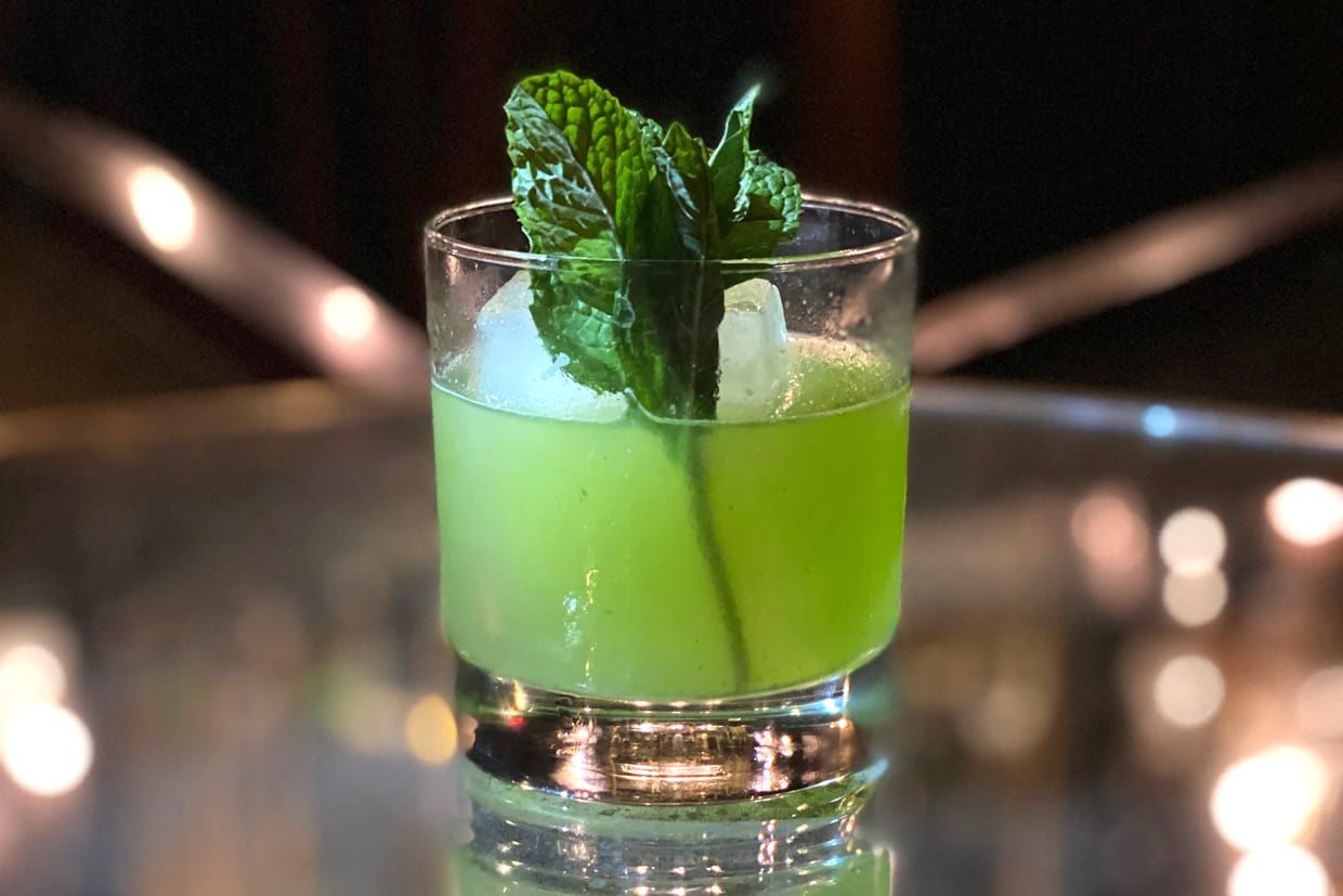 A green mocktail in a rocks glass with mint.