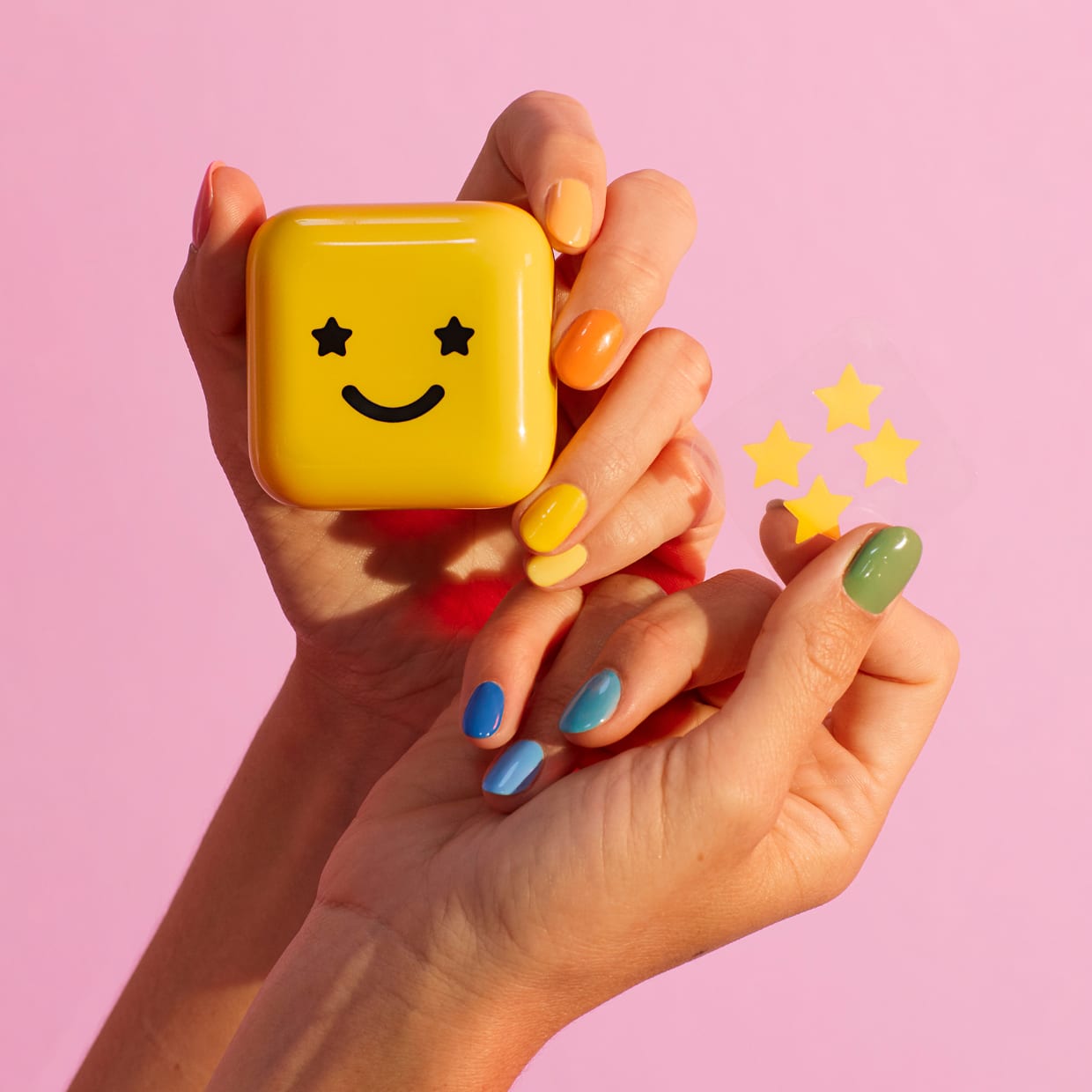 A pair of hands holding a yellow case with a happy face and a sheet of yellow star patches.