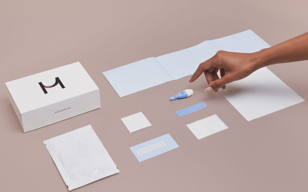 A flat lay of the Modern Fertility test kit with a hand reaching in.