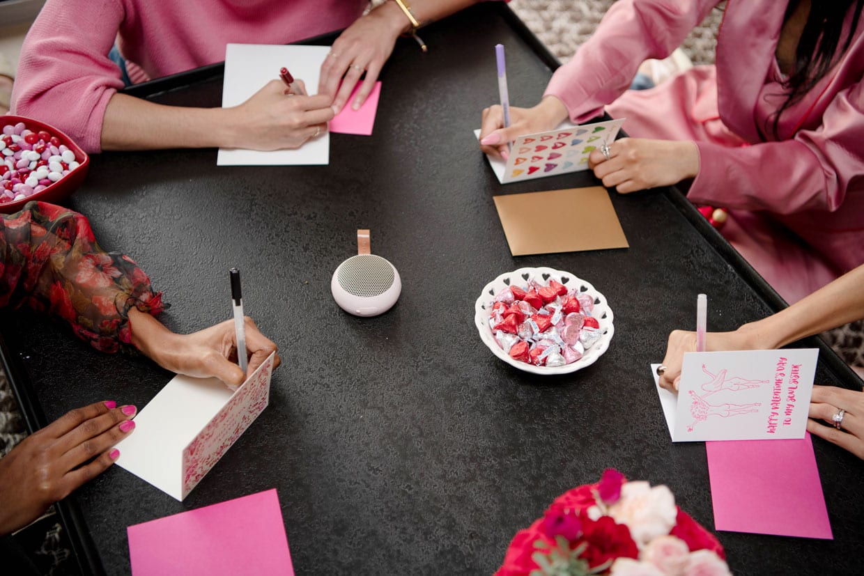 Four women writing in Galentine's Day cards.