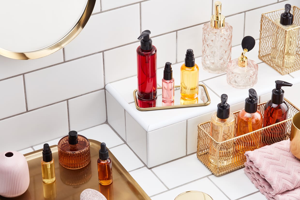 From above of arranged various cosmetic bottles on white shelf in bathroom filled with beauty products