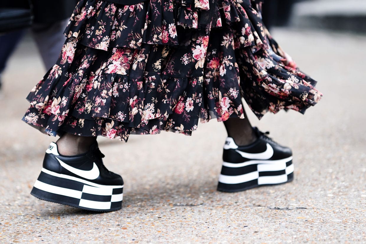 A person in a floral print ruffled dress and Nike black and white platform sneakers in London, Jan. 6, 2019.