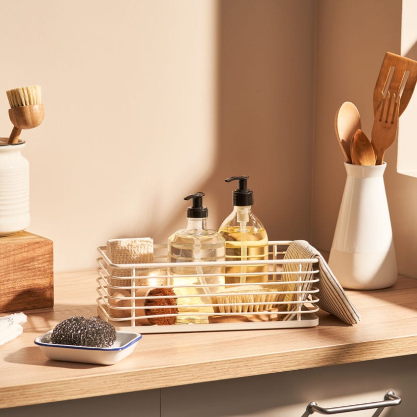A collection of assorted eco friendly sponges and brushes places on cupboard near natural detergents in modern kitchen.