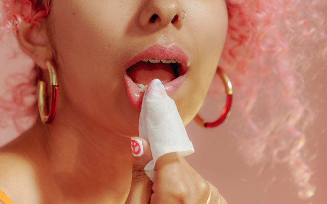 A woman using a makeup wipe to remove her lipstick.