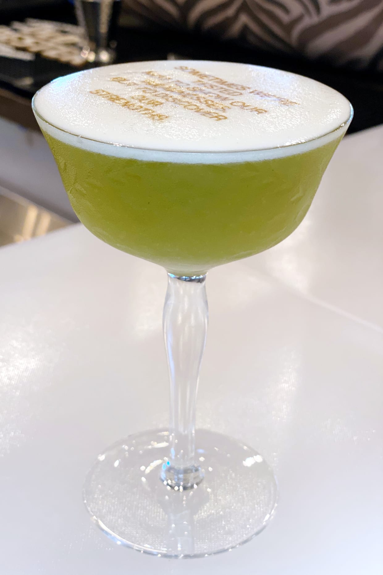 A green cocktail on a white counter.