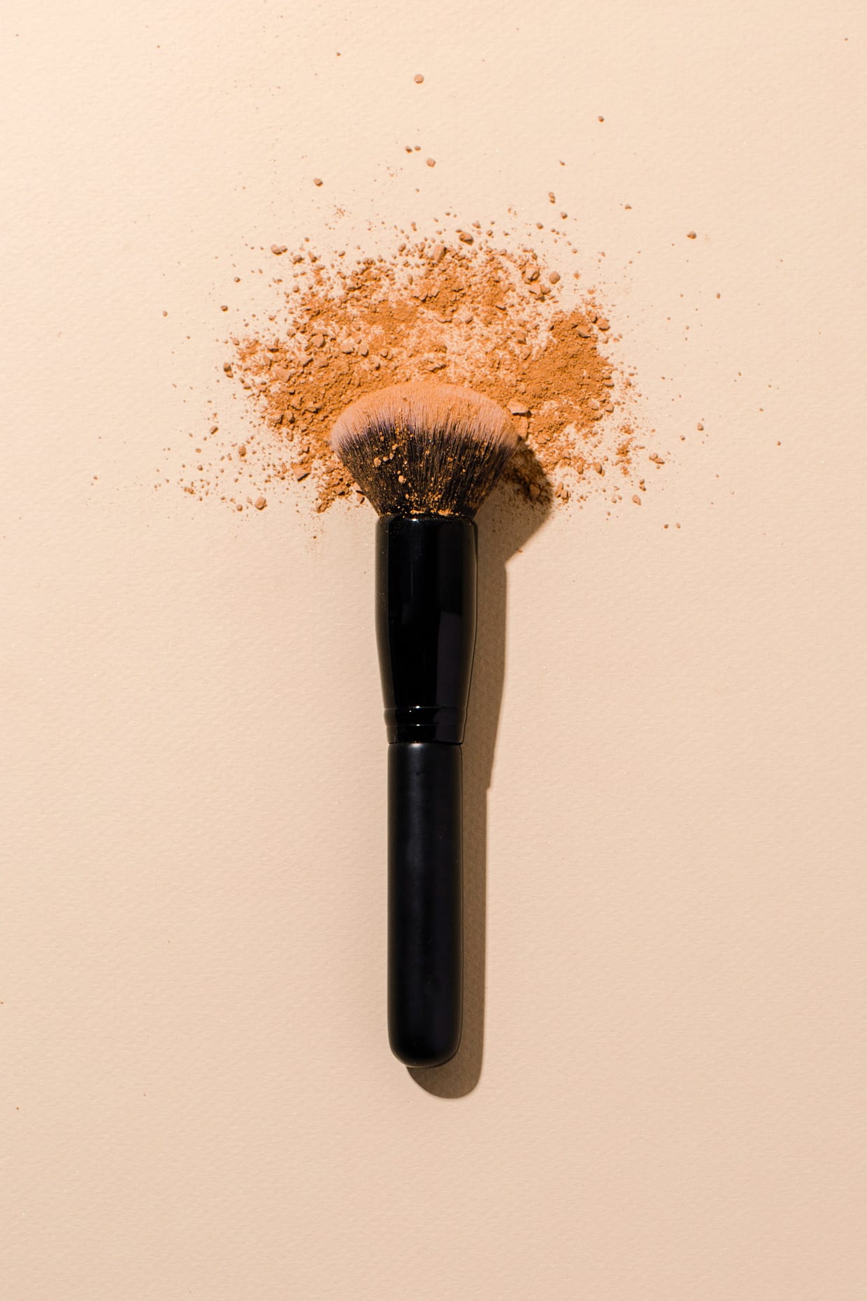 Still life of powder with black makeup brush.