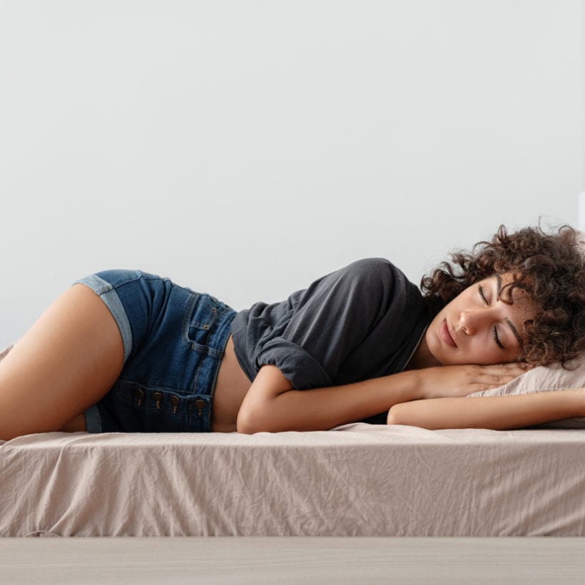 Young ethnic woman in a casual outfit sleeping on a comfortable bed in cozy room at home.