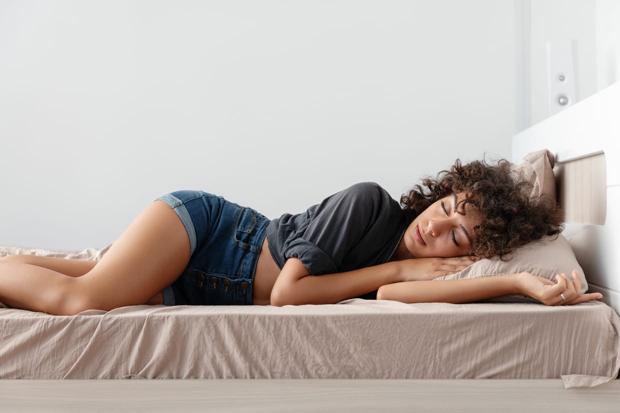 Young ethnic woman in a casual outfit sleeping on a comfortable bed in cozy room at home.