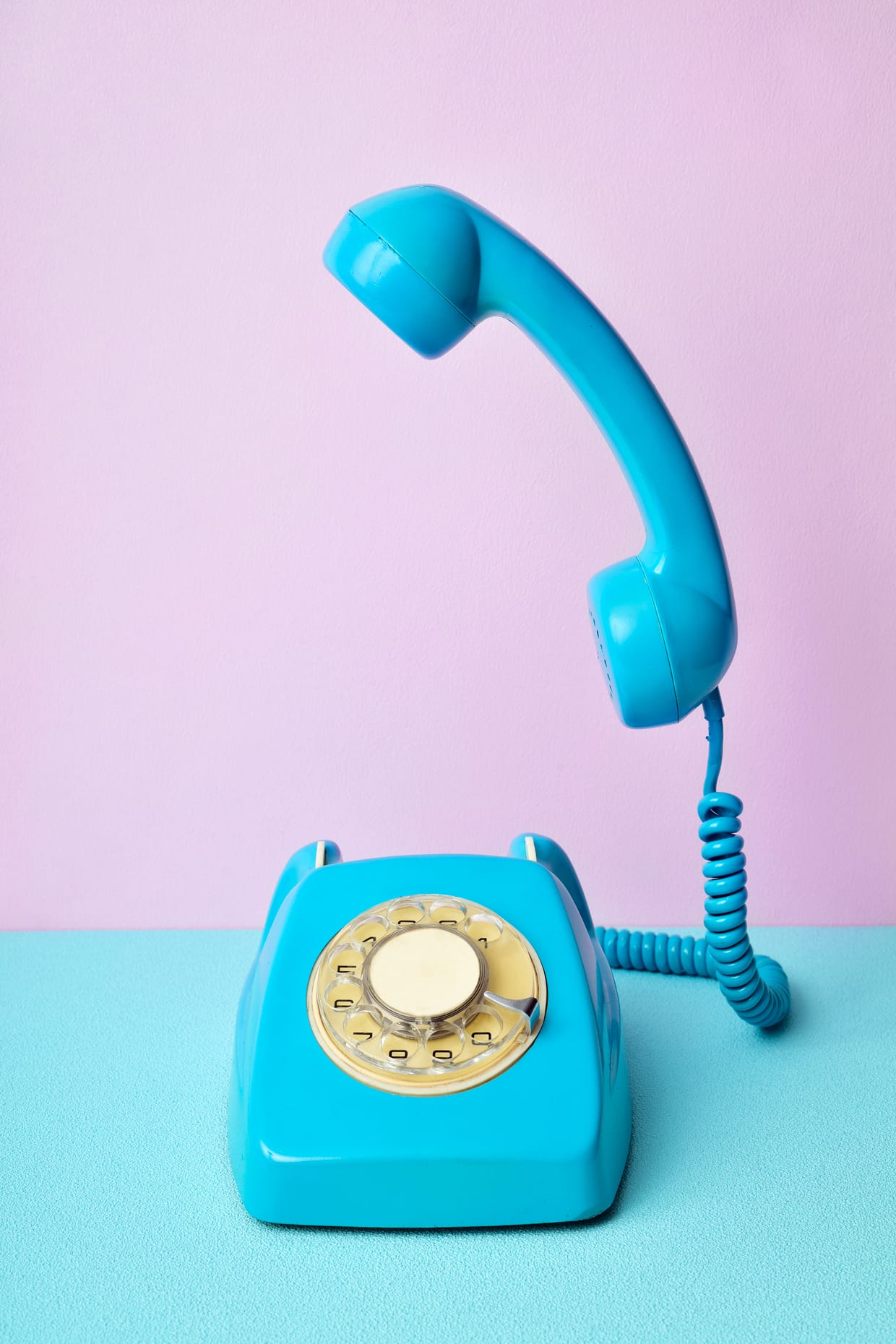 A light blue phone on a lavender and light blue background.