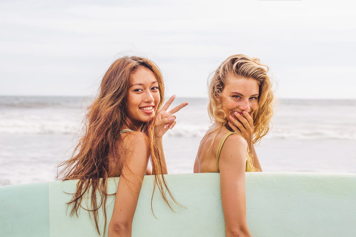 Two women holding a surfboard.