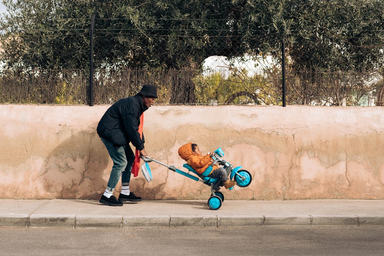 A Black man pushing his child on a stroller.
