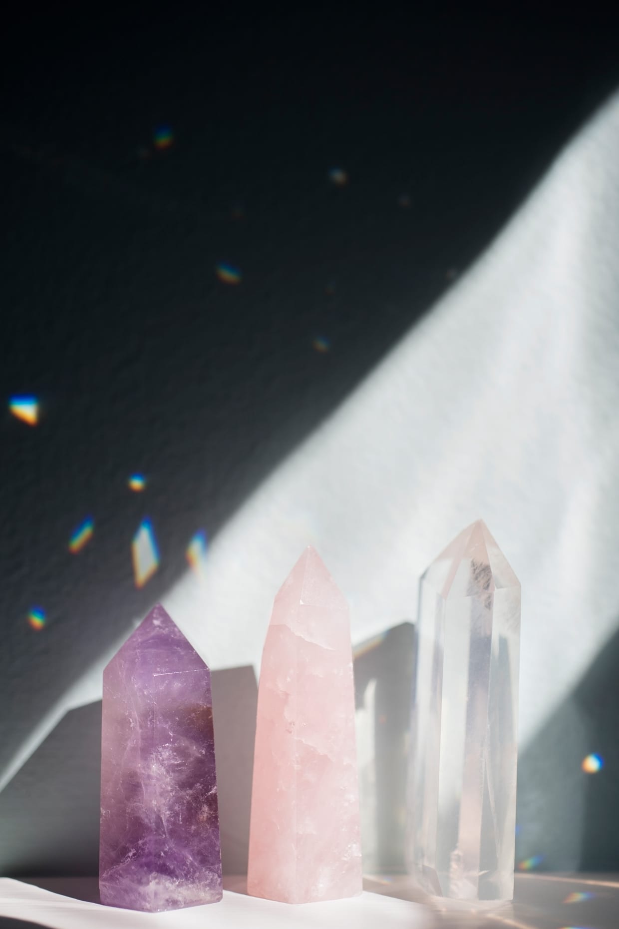 An amethyst, rose quartz and clear quartz crystal in a sliver of sunlight.