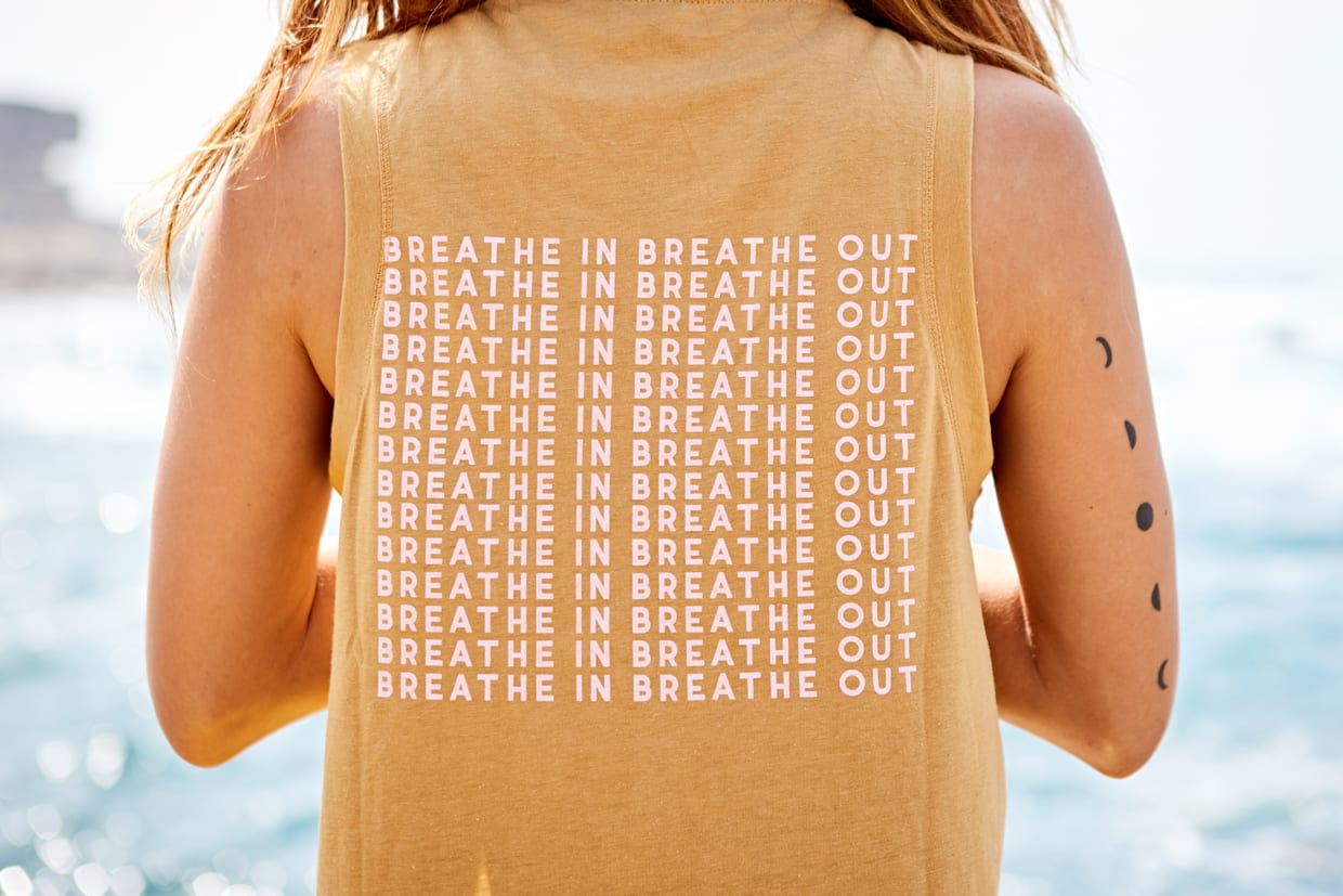 Back and shoulders of a woman wearing a yoga top that reads, 'Breathe in. Breathe out.'