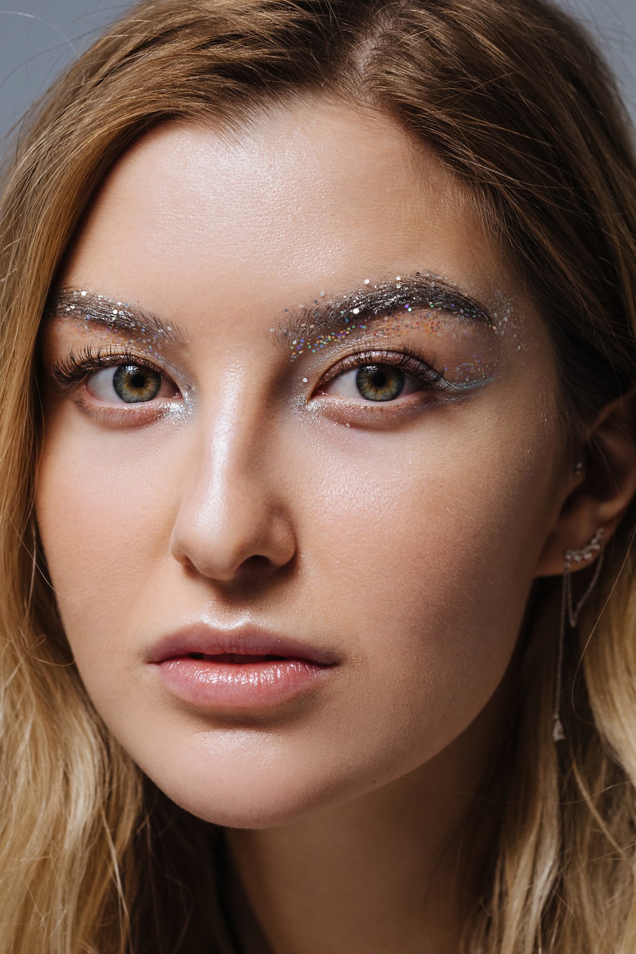 Close-up portrait of a woman with silver glitter on her eyelids and brows.