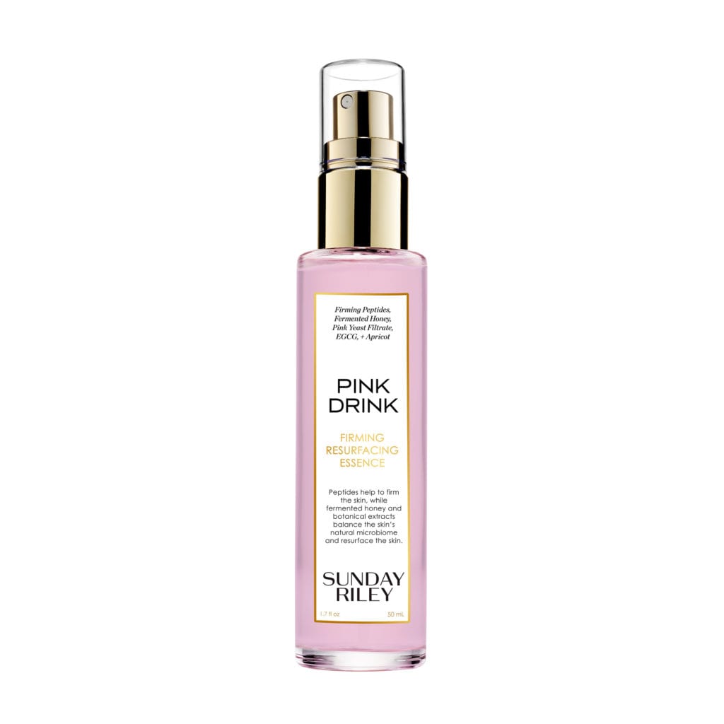 A spray bottle with a pink liquid and golden lid.