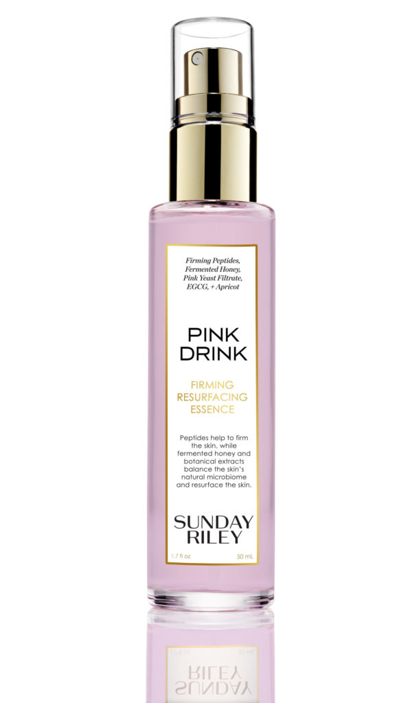 A spray bottle with a pink liquid and golden lid.