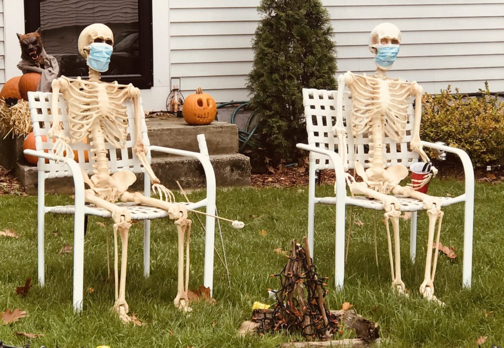 Probably too late, but even skeletons are wearing masks while toasting marshmallows on a lawn in Natick, Massachusetts, epitomizing what Halloween in 2020 is about because of the global Coronovirus Pandemic.