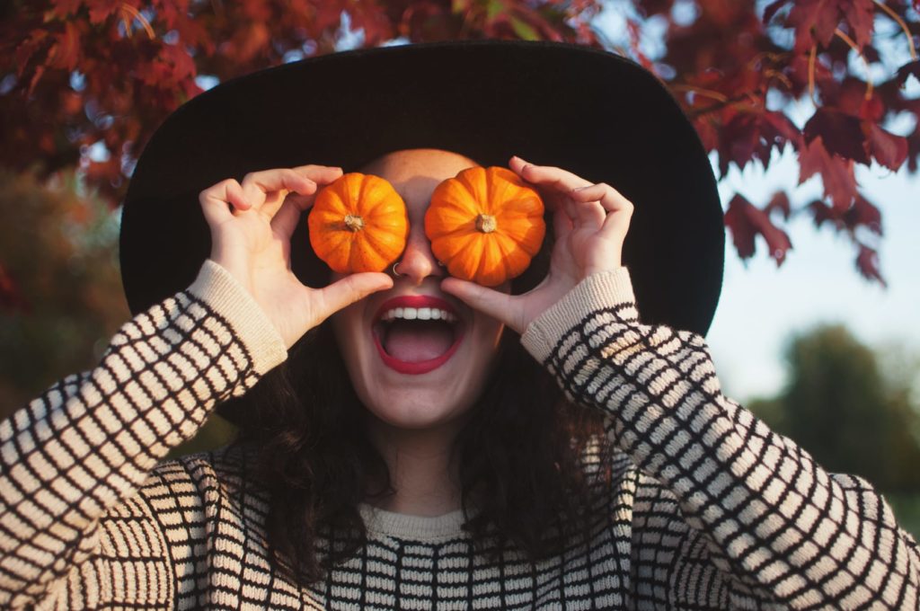 A young man with small pumpkins over his eye making a funny face.