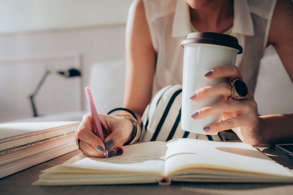 Hands of a woman writing notes in her personal planner.