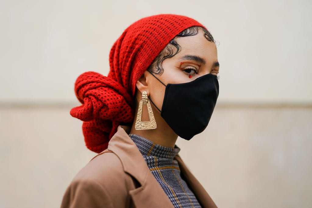 PARIS, FRANCE - SEPTEMBER 30: A guest wears a red wool scarf over the head, a black face mask, golden earrings, a turtleneck pullover, outside Kenzo, during Paris Fashion Week - Womenswear Spring Summer 2021, on September 30, 2020 in Paris, France. (Photo by Edward Berthelot/Getty Images)