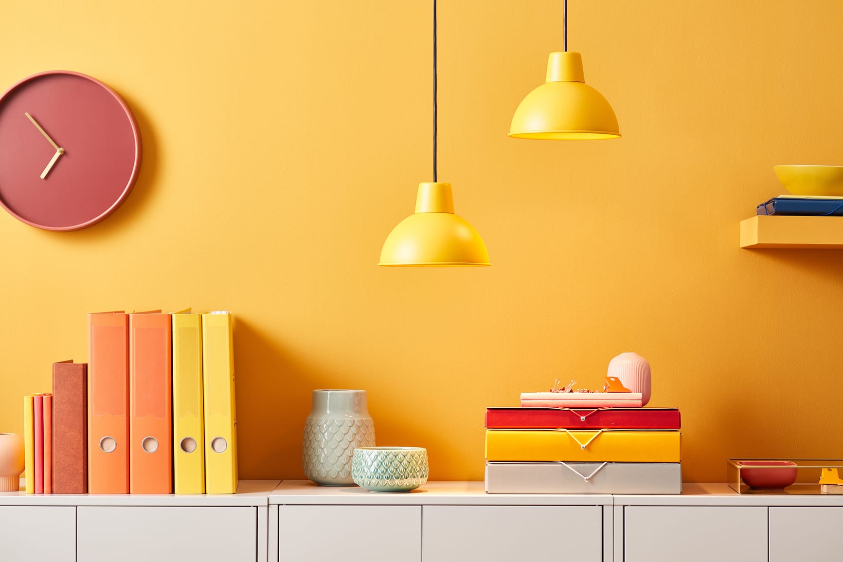 Creative interior of bright office with yellow wall and vivid folders composed on white cabinet under lamps