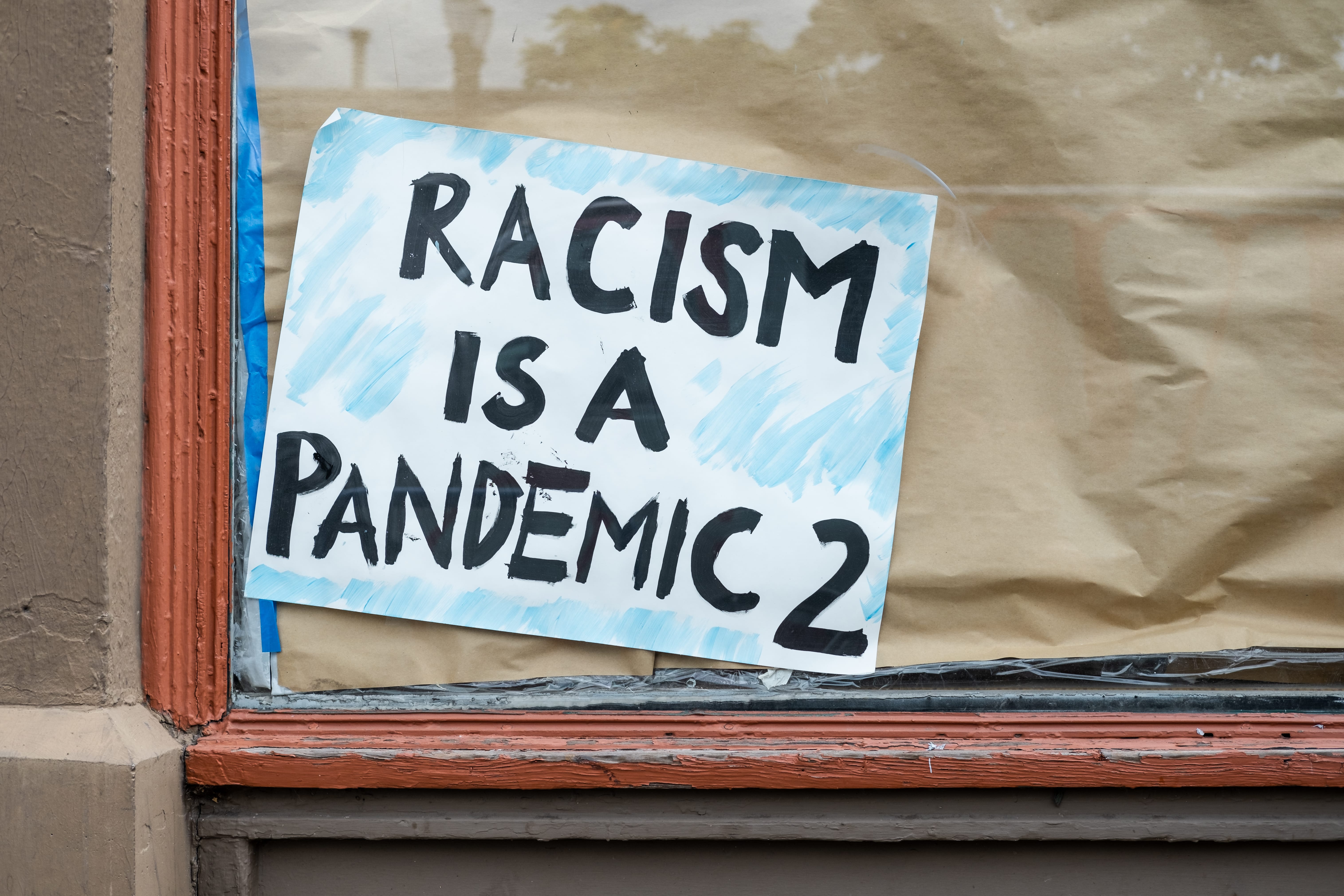 Sign in the window of a Portland, Oregon store saying that racism is a pandemic. Bringing attention to racists and systemic racism in America.