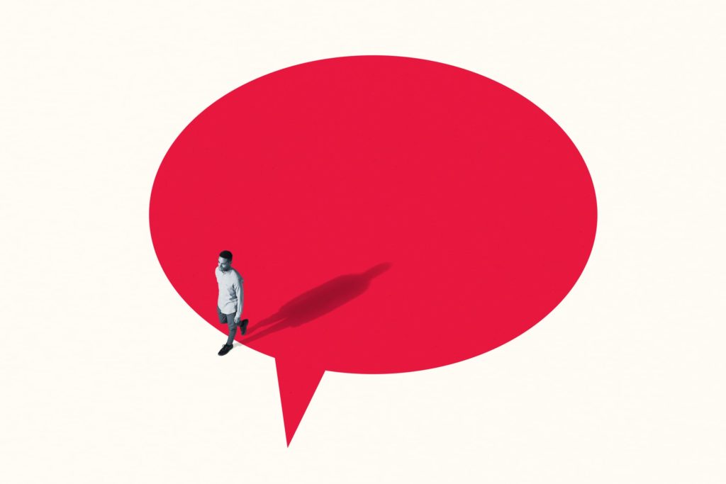 High angle view of young man walking out from vibrant red speech bubble against white background