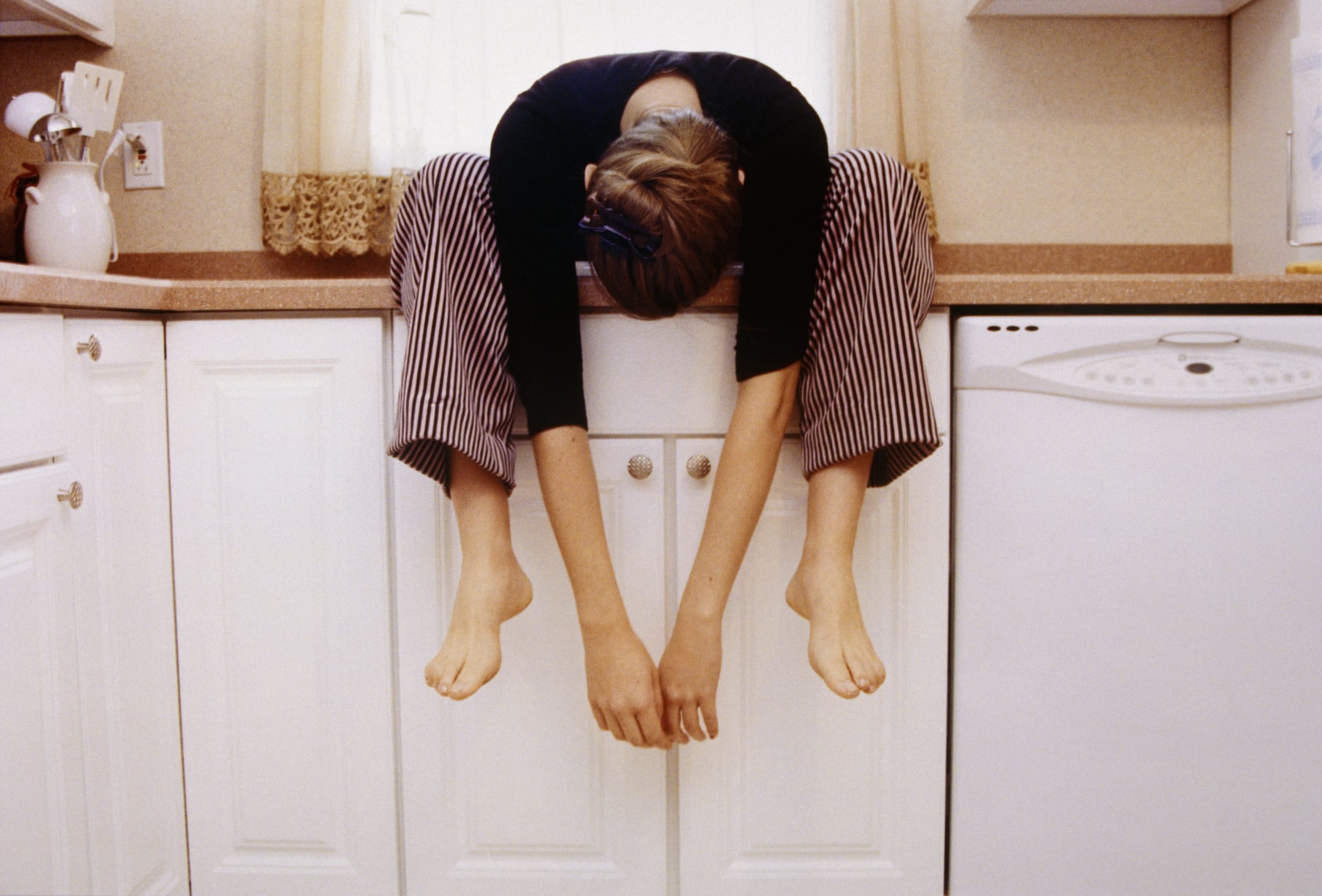Young Woman Sitting on Kitchen Cupboard