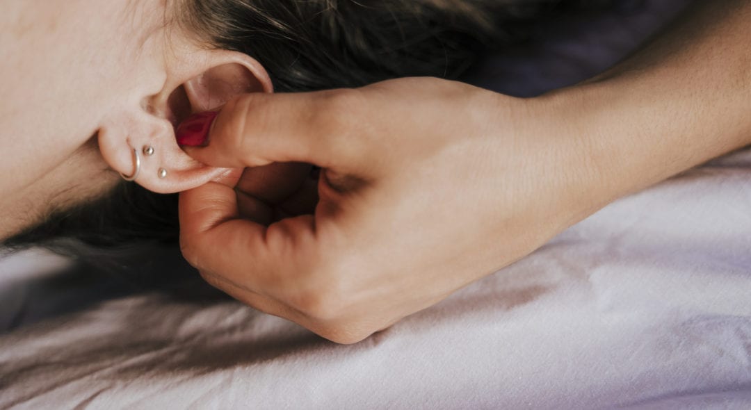 Close-up of female therapist giving ear massage to woman in health spa