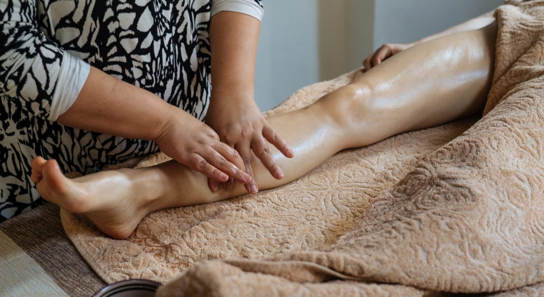 Crop anonymous client lying on table and getting massage from professional therapist at spa salon