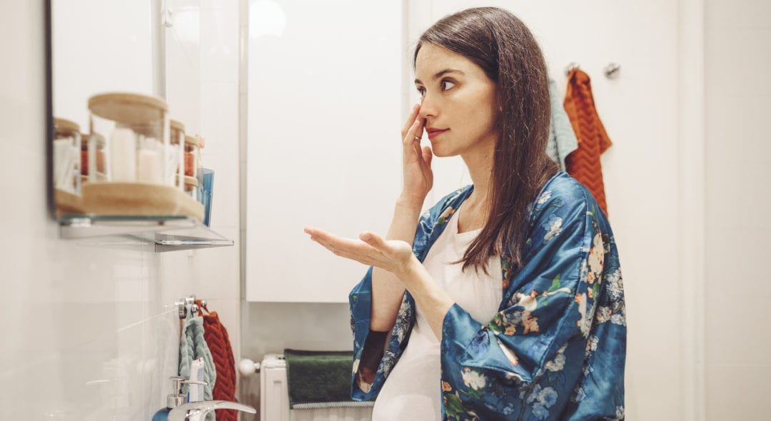 At home pregnant looking in the mirror