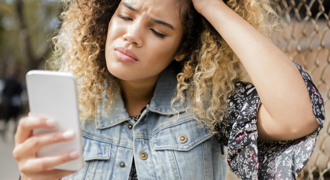 Unhappy Mixed Race woman texting on cell phone