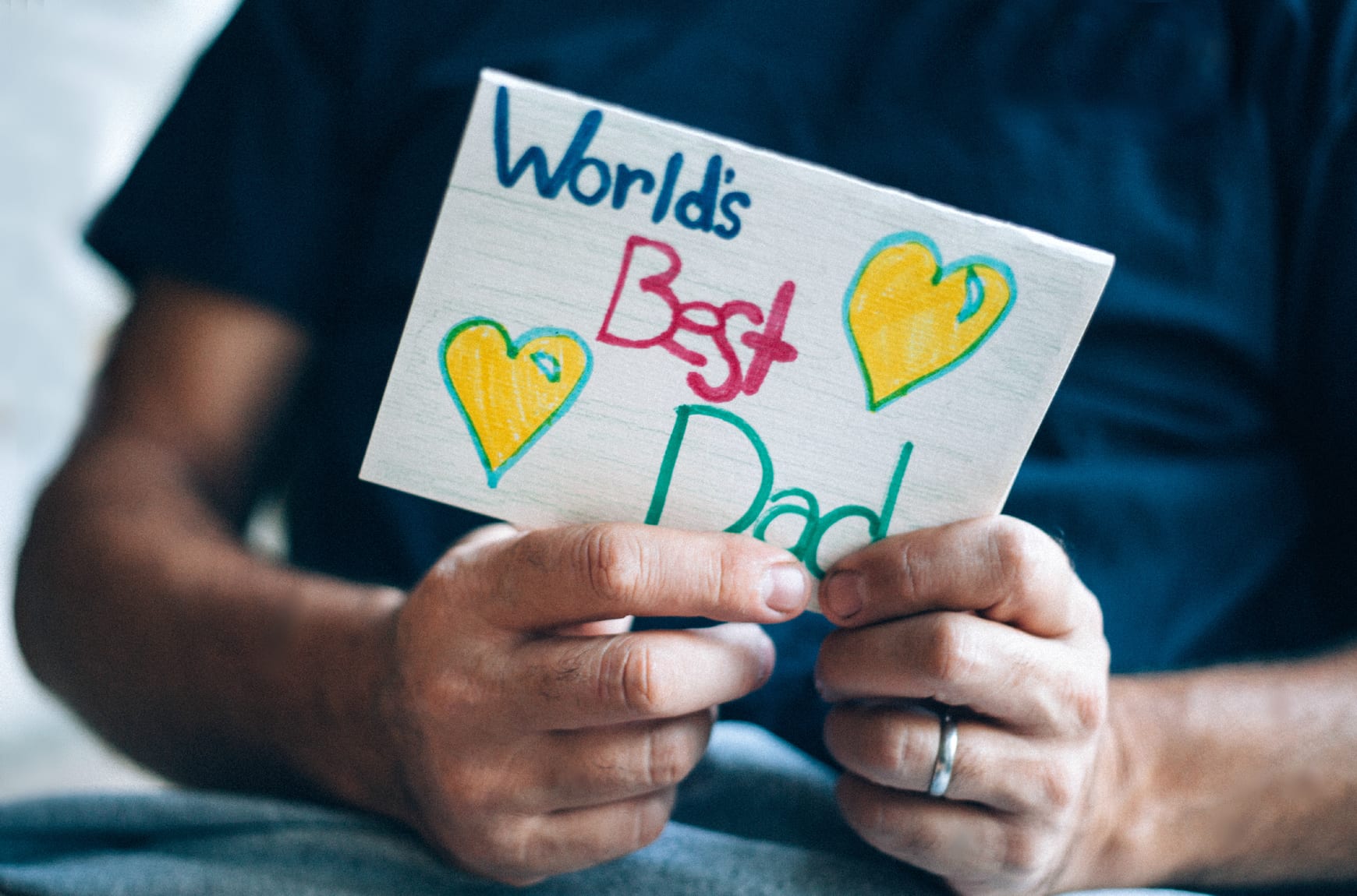 Father holding a homemade card that says World's Best Dad on Father's Day