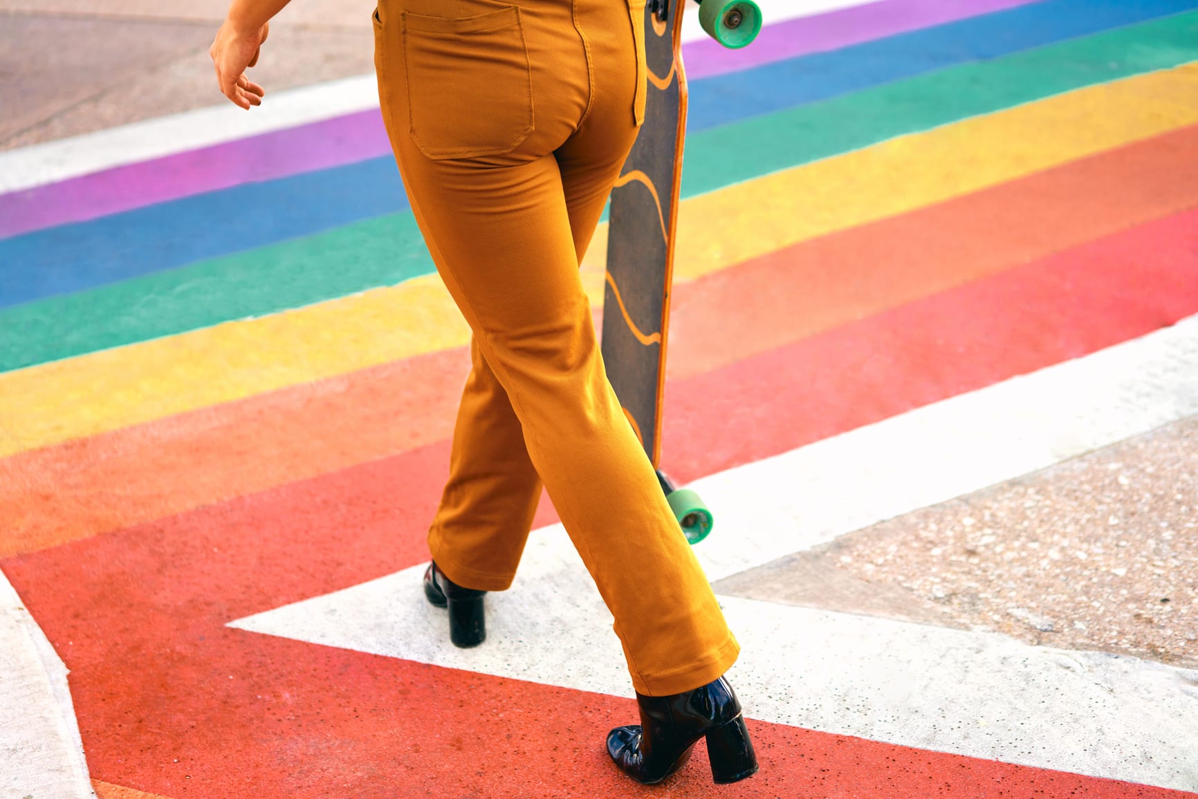 Stylish anonymous roller skater crossing a gay flag crosswalk in Dallas Texas.