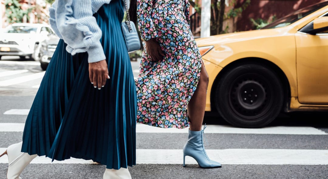 Two women walking in the city wearing blue and heels