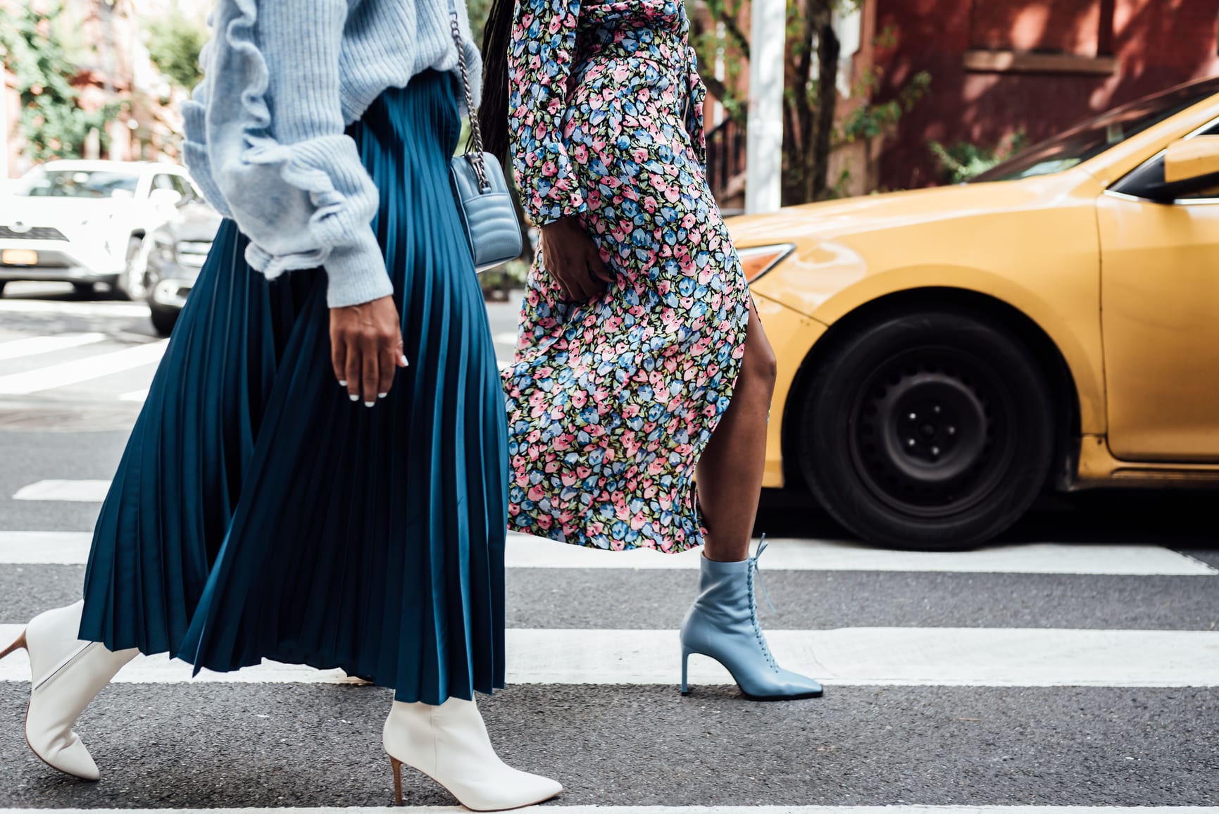 Two women walking in the city wearing blue and heels