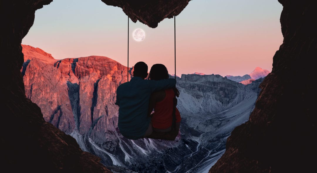 Composition of the Alps mountains during sunset with full moon and couple on swing from a heart shape cave.