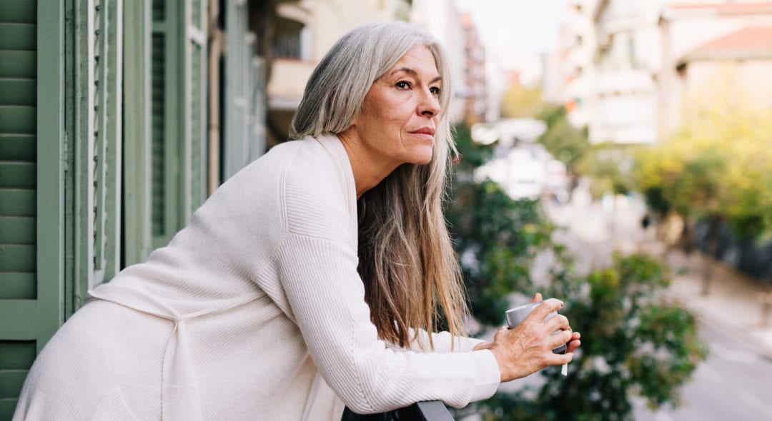 Woman wearing pajama holding a tea on balcony.
